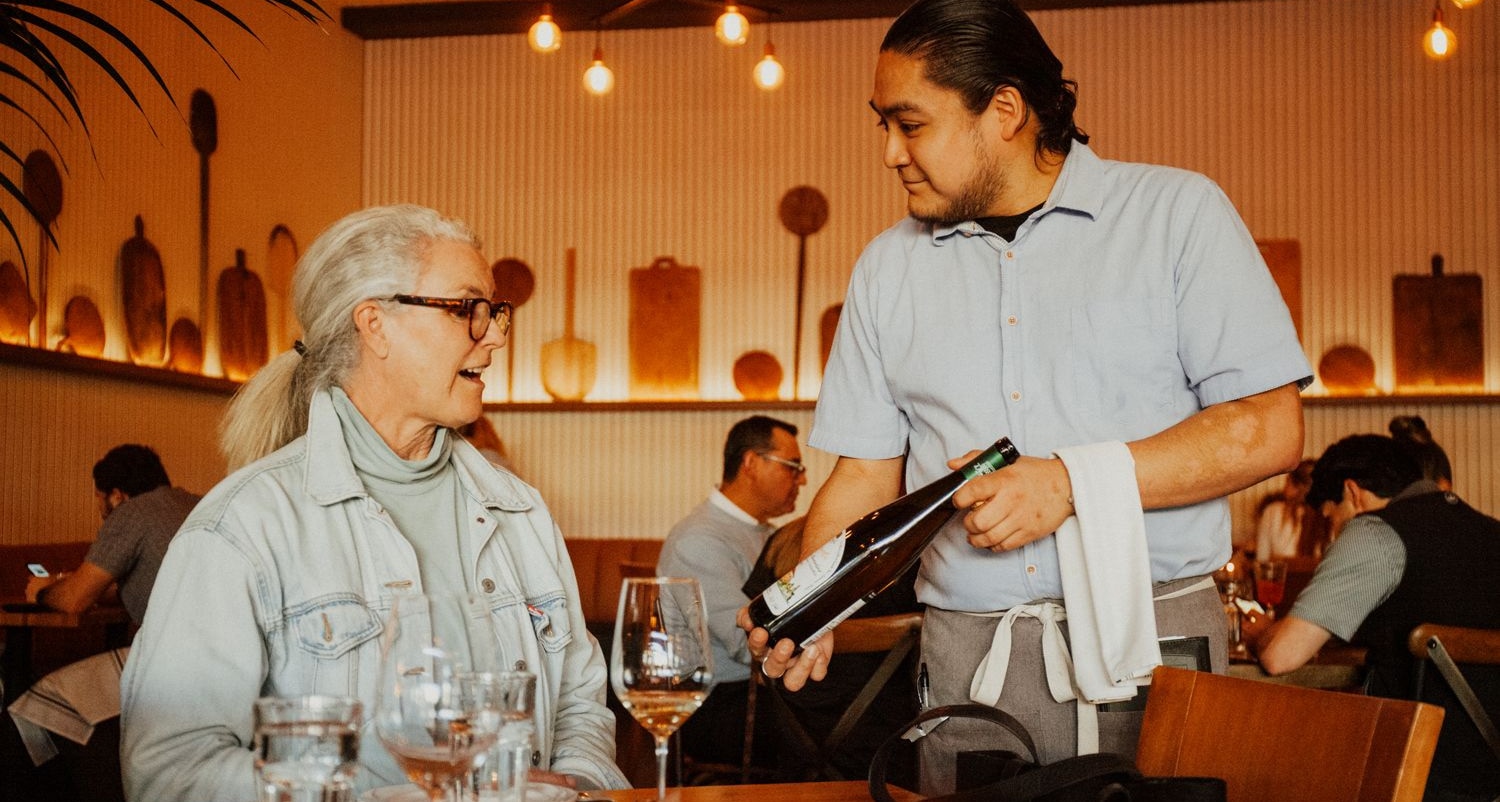 Man showing a bottle of wine to a woman at Piatello