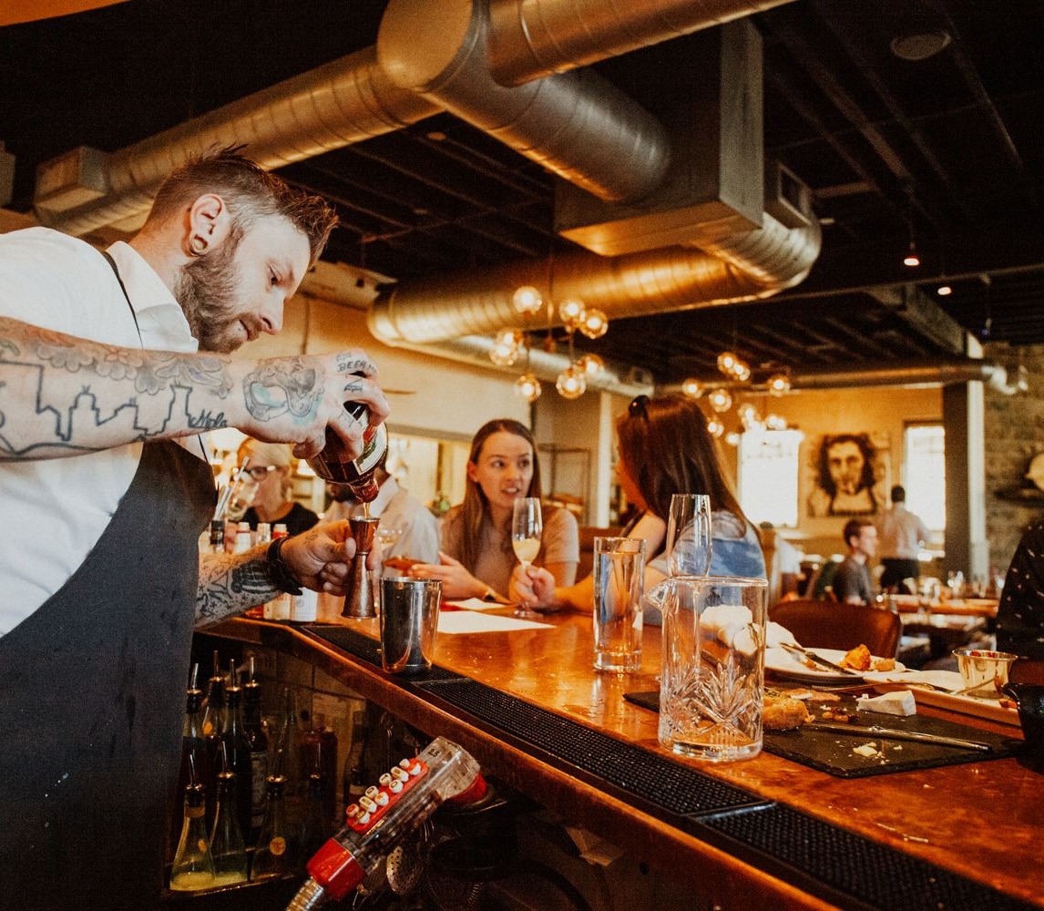 Dramatic shot of a man making a cocktail behind a bar
