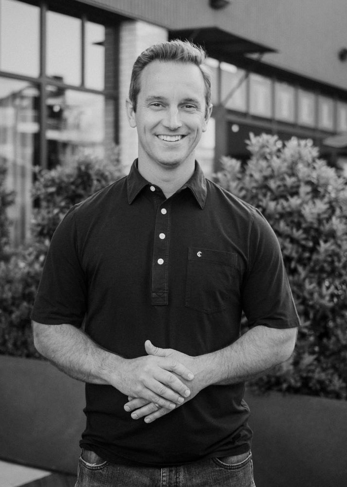 Black and white photo of Marcus Paslay standing outside, wearing a polo